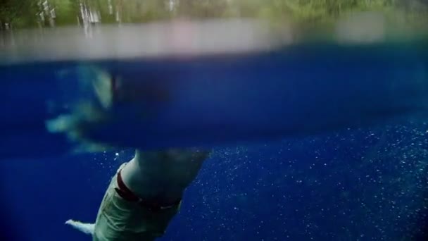 Молодой человек любит плавать под водой в чистом озере — стоковое видео