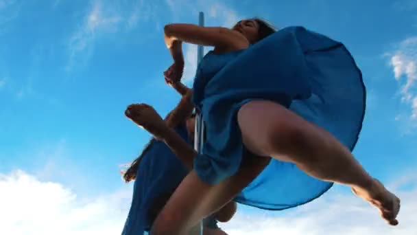 Dos bailarinas con vestidos azules bailando en el pilón contra el cielo — Vídeos de Stock