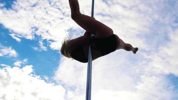 Jovem mulher sexy em lingerie preta executa uma pole-dance contra o céu — Vídeo de Stock