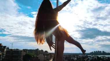 Cityscape karşı pilon üzerinde günbatımında yapıyor uzun saçlı seksi kadın