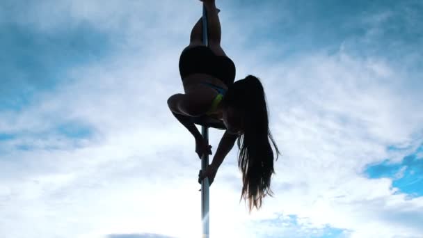 Flexible female pole-dancer in sports lingerie exercising on the pylon at sunset — Stock Video