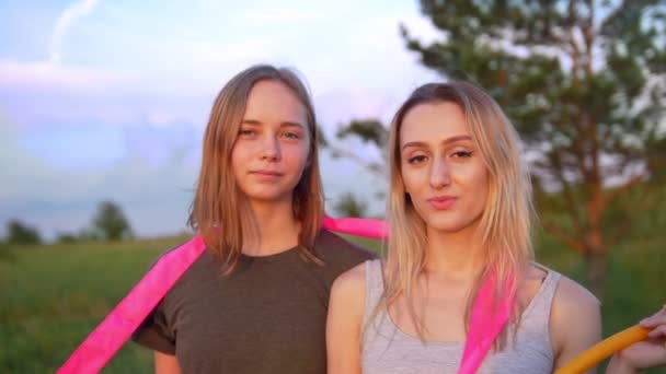 Portrait de deux jeunes femmes gymnastes avec équipement de gymnastique sur la colline au coucher du soleil d'été — Video