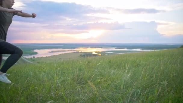 Young sporty woman performing a flip on the grass at summer sunset — Stock Video