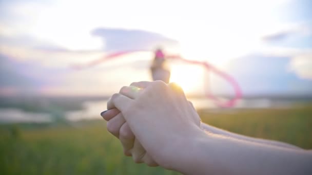 Mãos femininas libera borboleta na frente de exercícios de mulher com fita ginástica ao pôr do sol — Vídeo de Stock