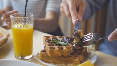 Erkek ellerini keser bir bıçak ve çatal restoranda nefis bir Belçikalı Waffle