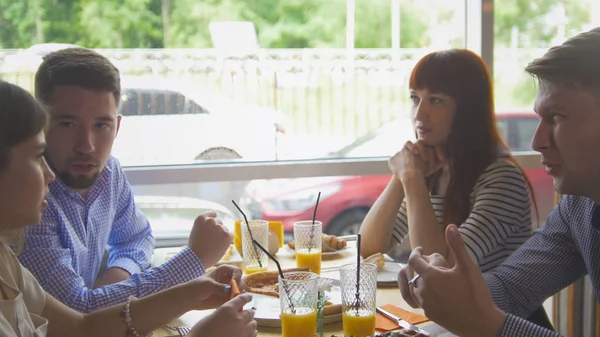 Unga glada vänner njuter en middag och umgås i restaurang — Stockfoto