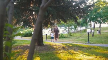 Gün batımında parkta yürüyüş elele torunu ile Olgun kadın