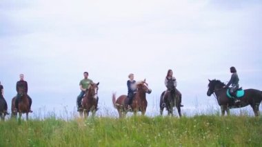Equestrians ata ayakta arasında geniş çayır üzerinde Grup