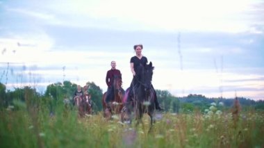 Çayır çiçeklerle aracılığıyla genç Binicilik at sırtında grup rides