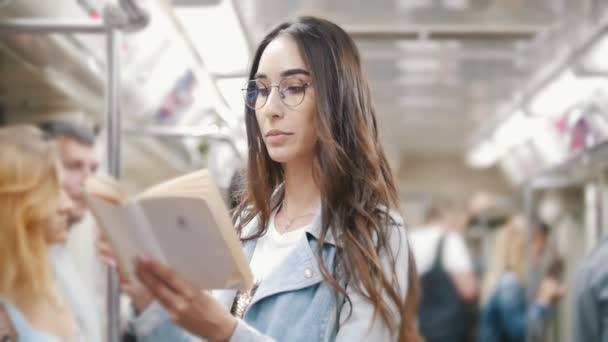 Flickan går till tunnelbanan och läser en bok — Stockvideo