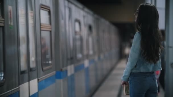 Κορίτσι φαίνεται γύρω, στέκεται στην πλατφόρμα, διερχόμενο τραίνο, αργή κίνηση — Αρχείο Βίντεο