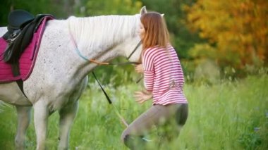 Genç kadın yaz alanında ata eyer giderir