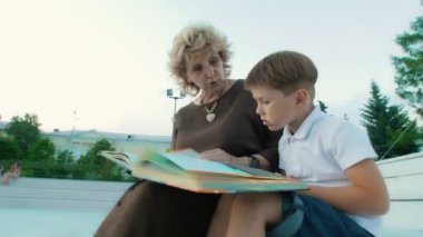 Büyükanne ve torunu yaz günü parkta adlı bir kitap okuma