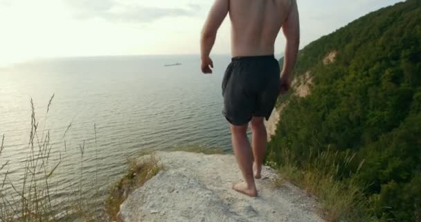 Giovane seduto sul bordo di una scogliera e guardando l'ampio fiume — Video Stock