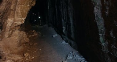 Grup Genç yürüyüşçü kask içinde karanlık mağaranın ve etrafa araştırıyor