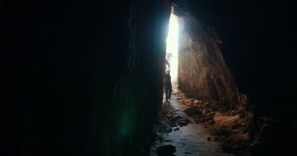 Un gruppo di giovani esploratori in casco entra nella caverna oscura — Video Stock