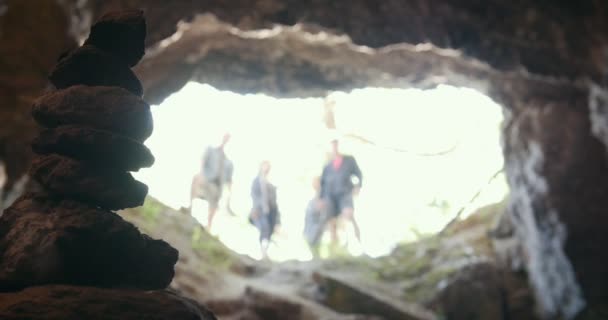 Handgemaakte stenen toren in grot in de voorkant van de groep van vrienden in helmen — Stockvideo