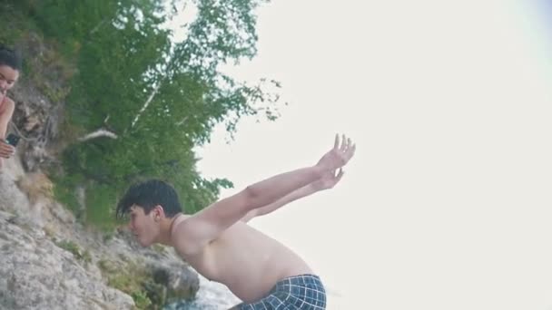 Ο τύπος κάνει ένα flip βουτούν στο νερό από το βράχο, κάτω όψη, αργή κίνηση — Αρχείο Βίντεο