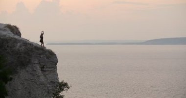 Uçurumun kenarında deniz kenarında dans siyah elbiseli Genç kadın