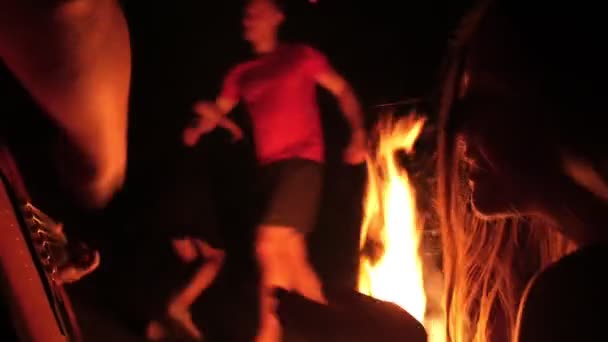 Amigos alegres dançando divertindo músicas com uma guitarra na fogueira à noite — Vídeo de Stock