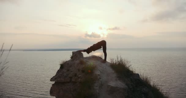 Junge Frau beim morgendlichen Yoga auf dem großen Stein am Meer — Stockvideo