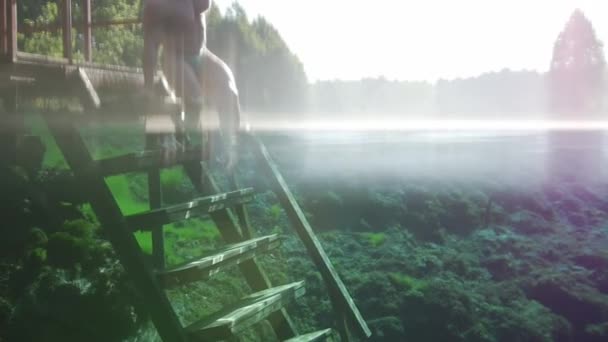 Joven hombre por las escaleras en el lago azul claro — Vídeo de stock