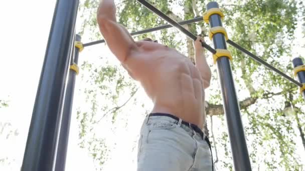 Молодой человек выполняет силовые упражнения на горизонтальной панели — стоковое видео