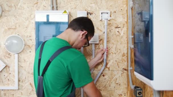 Joven estudiante electricista instala los conductores eléctricos en taller — Vídeo de stock