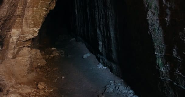 Gruppe junger Freunde mit Helmen spaziert durch die dunkle Höhle — Stockvideo