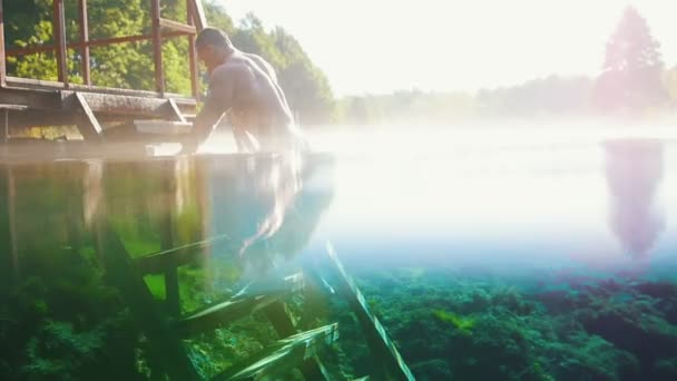 Muskulöser Mann steigt die Treppe vom blauen See hinauf — Stockvideo