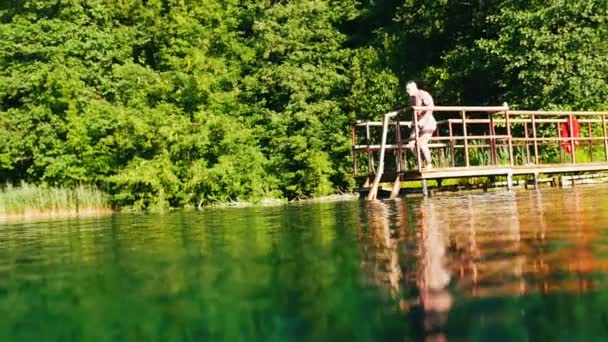 Svalnatý mladík skočil do modré vody — Stock video