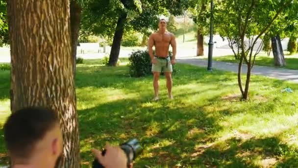 Jeune homme bodybuilder posant pour photographe dans le parc — Video