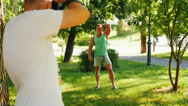 Muscular guapo culturista posando a fotógrafo en el parque — Vídeos de Stock