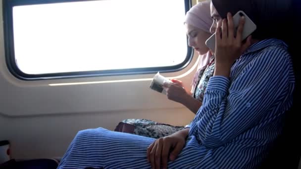 Dvě muslimské ženy mluví telefon ve vlaku — Stock video