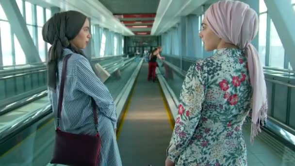 两名穆斯林妇女乘自动扶梯在机场旅行 — 图库视频影像