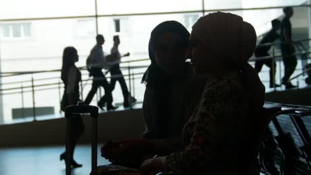 Duas mulheres muçulmanas conversam na sala de espera do aeroporto — Vídeo de Stock