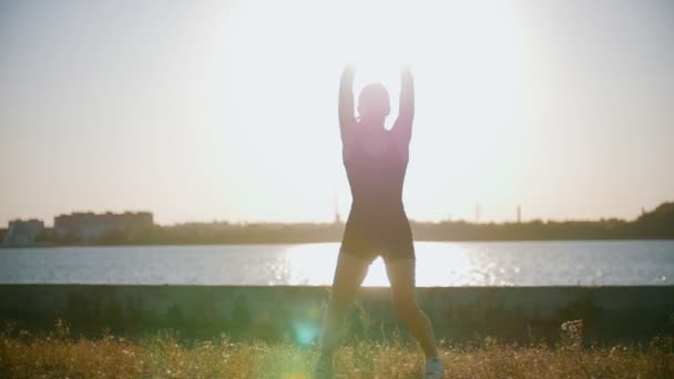 Атлетическая женщина тренируется против солнца — стоковое видео
