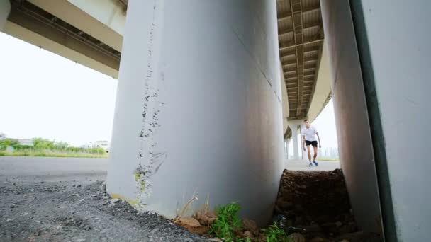 Человек делает трюк под мостом, замедленная съемка — стоковое видео