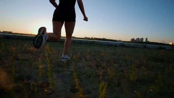 Atletische jonge vrouw loopt naar de rivier en kijkt naar de zonsondergang — Stockvideo