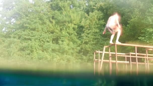 Young man back flipping off the bridge into water — Stock Video