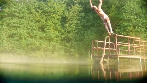 젊은 남자가 다시 맑은 물에 다리에서 뛰어 내리고 — 비디오