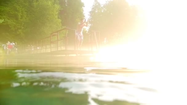 Young man jumps off the bridge into clear water — Stock Video