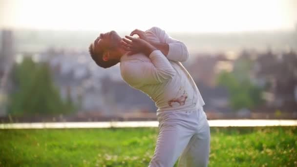 Deportista atlético amasa su torso antes de bailar capoeira en la hierba, verano — Vídeos de Stock
