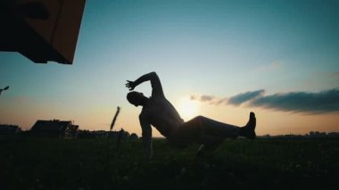 Yetenekli adam Capoeira çimenlerin üzerinde günbatımında, yaz dans.