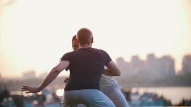 Çok güçlü erkekler dans capoeira, becerilerini göstermek bir ot, gülümseme, bir gün batımında fight