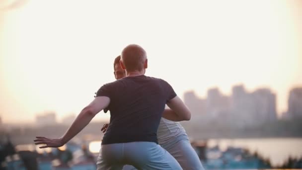 Sehr starke Männer zeigen Fähigkeiten des Capoeira-Tanzes, kämpfen auf einem Gras, lächeln bei Sonnenuntergang — Stockvideo