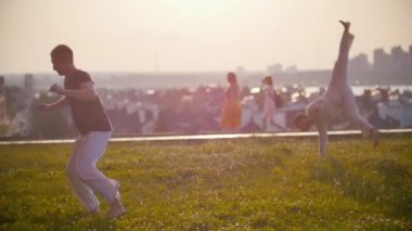 Erkekler güçlü vücut dans capoeira ile geçen insanlar ve güzel gün batımı arka planı dans