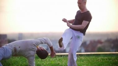 Sadece güçlü adamlar becerileri karşı güzel çimenlerin üzerinde Capoeira Brezilya savaş sanatı yaz günbatımı göstermek.