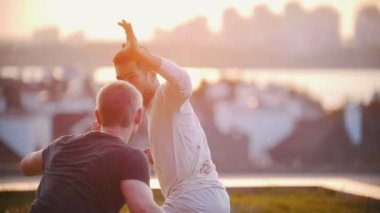 İki adam bir spor vücut ile şehir ve yaz günbatımı güzel manzarasına karşı bir mücadele düzenledi