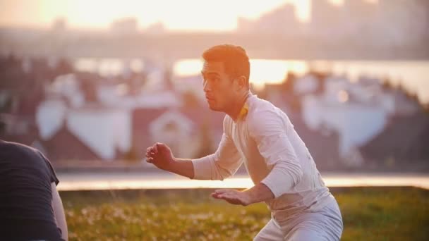 Dos hombres con un físico deportivo bailan capoeira al aire libre en una hermosa puesta de sol de verano — Vídeos de Stock